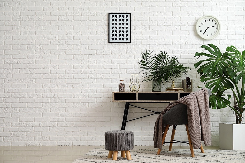 Decorate a room with indoor plants, ottoman foot stool, a chair and a desk